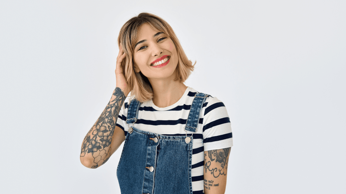 Smiling woman with a stylish blonde bob and soft fringe, dressed in denim and stripes. Fresh spring haircut and colour by Nicolas Ablitt Hair Studio in Corringham, Essex – experts in seasonal hair updates and modern, low-maintenance styles.